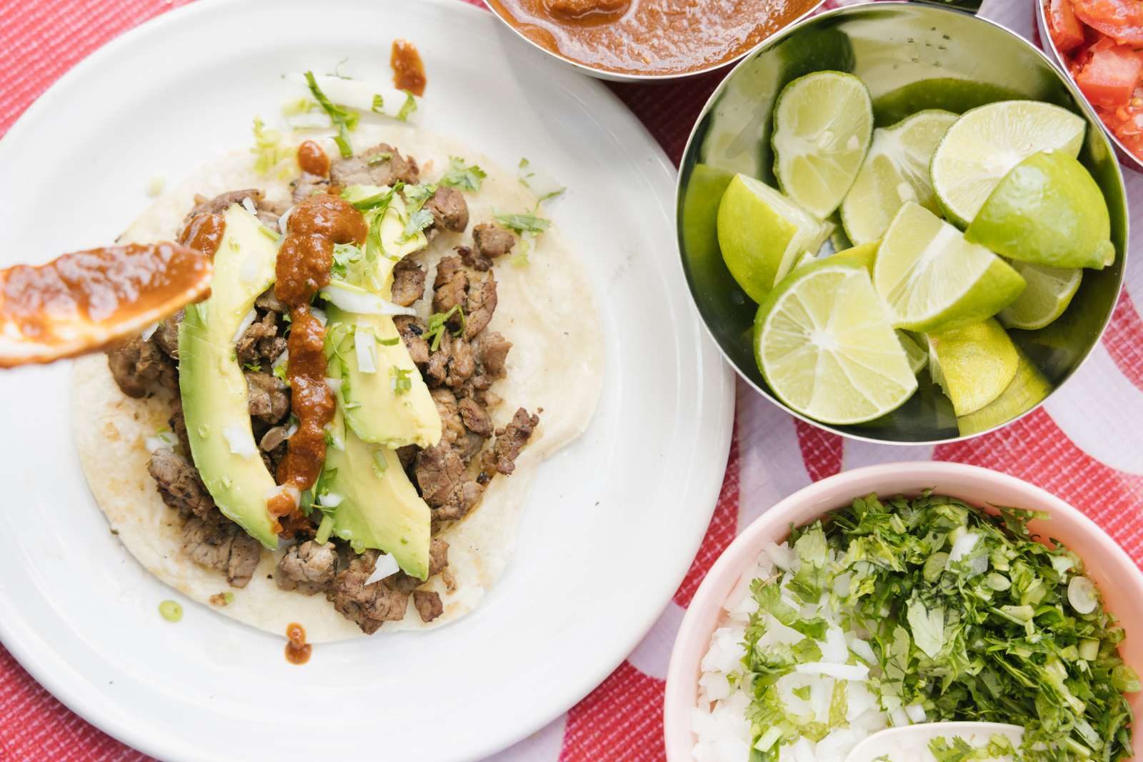 A taco with avocado and salsa, limes and herbs at El Greco